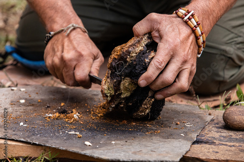 Closeup of man hand during demonstration of traditional method for fire lighting using chaga mushroom to keep fire alive at world and word festival photo