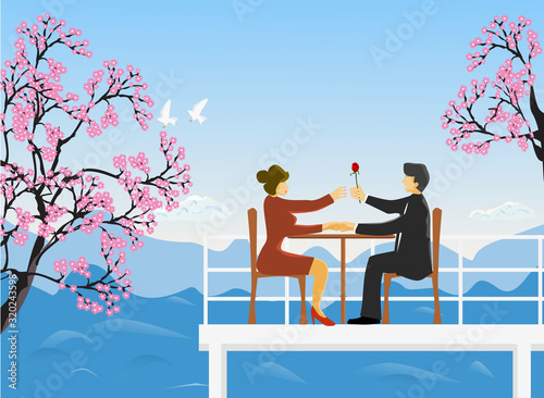 The couple sat on a wooden chair on the rooftop, a man handed red roses to women, cherry blossoms and mountains and the sky as the background