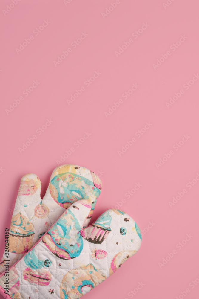 Kitchen glove potholders with donut patters isolated on a pink background. Flat lay, Space for text, copy space. Cooking concept. Kitchen glove potholders with donut patters isolated on a pink background. Flat lay, Space for text, copy space. Cooking concept.