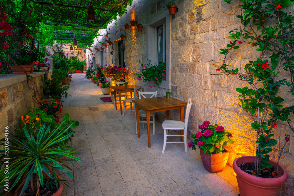 Fototapeta premium Harmonious narrow street and street cafe decorated with flowers