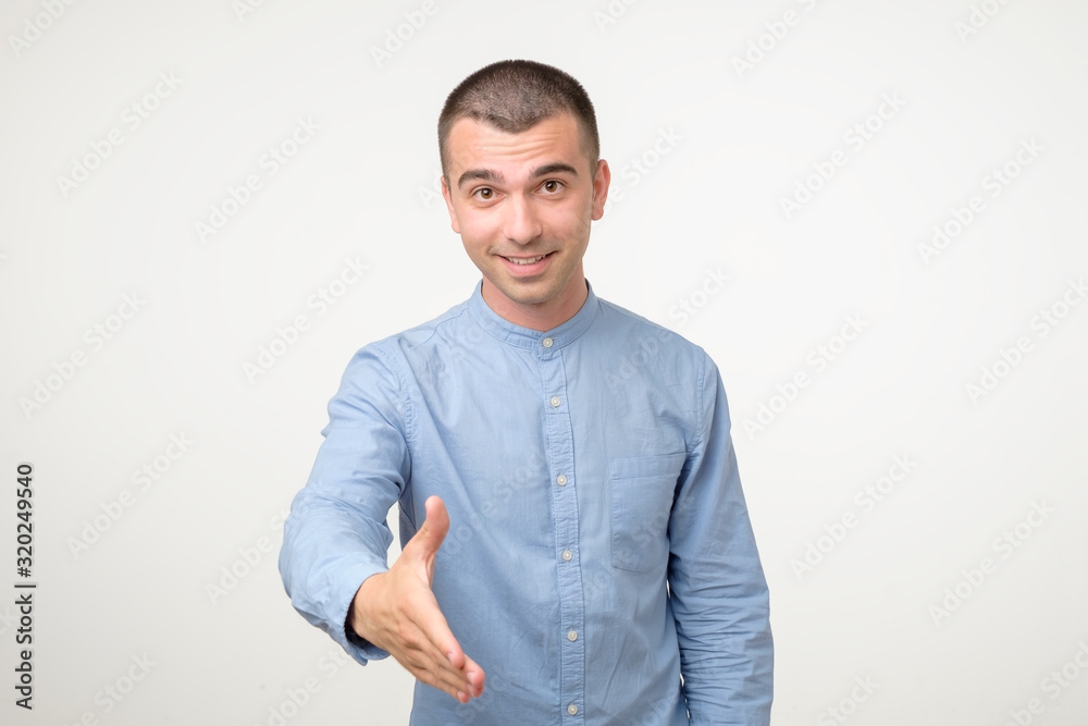 Welcome concept. Handsome young hispanic man stretching out hand for shaking Welcome concept. Handsome young hispanic man stretching out hand for shaking