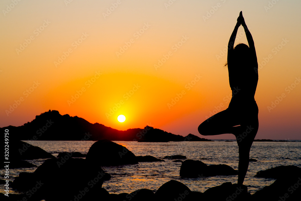 A girl silhouette doing yoga at sunset