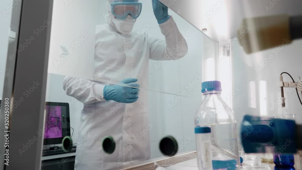 Chemist in protective clothes works with samples in medical laboratory. Concept of working on vaccine for new chinese virus Chemist in protective clothes works with samples in medical laboratory. Concept of working on vaccine for new chinese virus