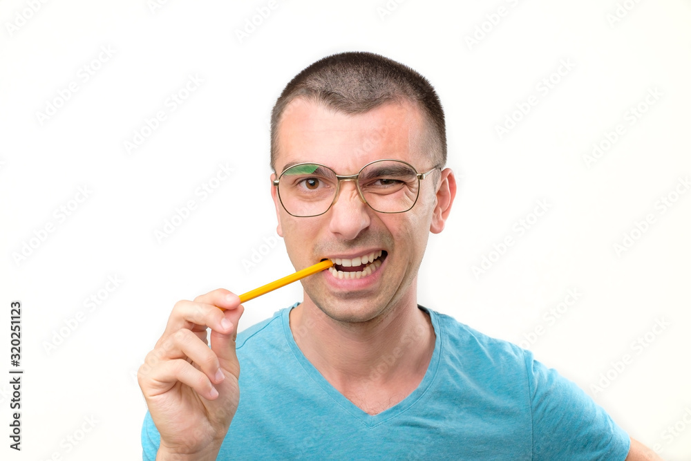 Young hispanic man in glasses is thinking about something with pencil