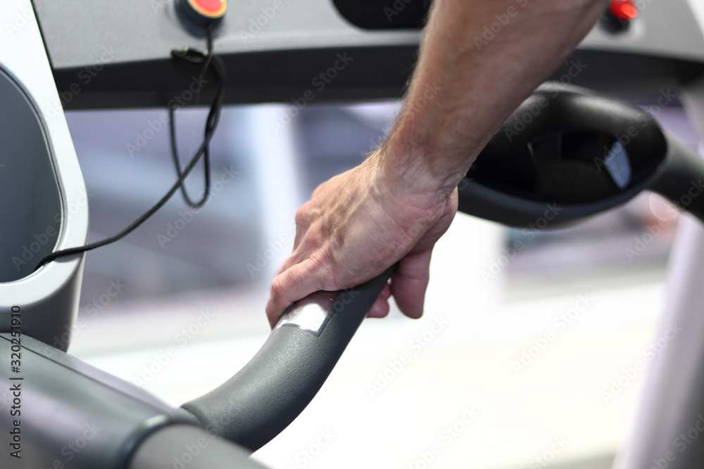 Male runner walking on treadmill in Health Club. Focus on hand. Male runner walking on treadmill in Health Club. Focus on hand.
