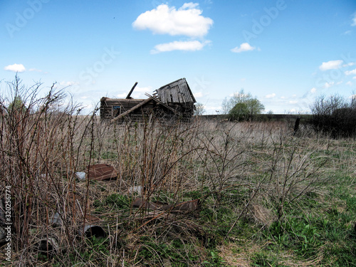 Old wooden abandoned ruined building in a field in summer in Russia