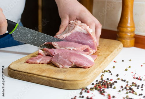 Slicing meat at home on a kitchen board and pepper