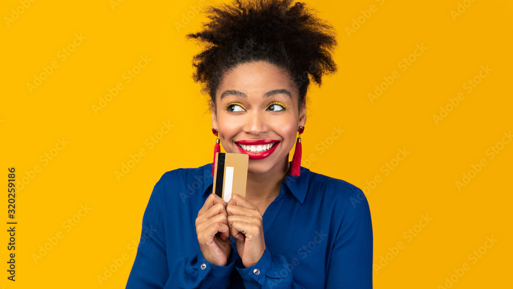 Black woman holding credit card and looking up - obrazy, fototapety, plakaty 