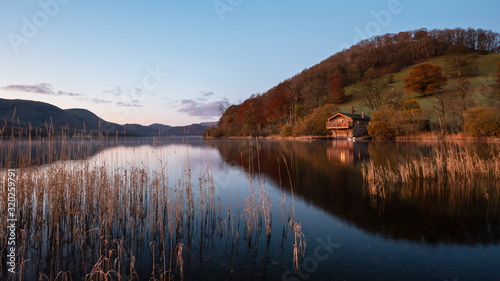 Epic vibrant sunrise Autumn Fall landscape image of Ullswater in Lake District with golden sunlight photo