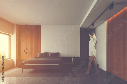 Woman walking in white and wooden bedroom