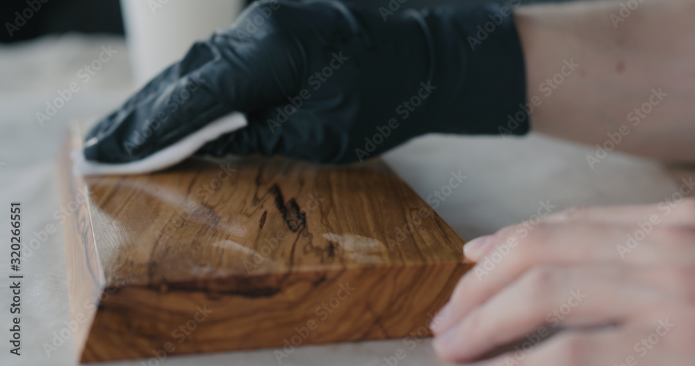 woodworker applying oil finish to olive wood board woodworker applying oil finish to olive wood board