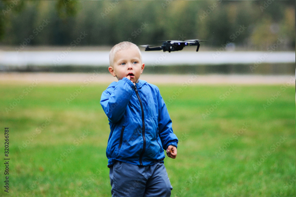 Curious boy watching drone floating in the air with wonder Curious boy watching drone floating in the air with wonder