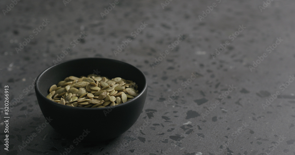 pumpkin seeds in black bowl on terrazzo countertop with copy space pumpkin seeds in black bowl on terrazzo countertop with copy space