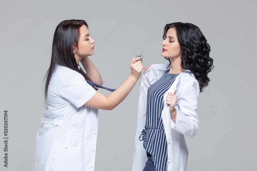 Female doctor examining another woman with stethoscope Female doctor examining another woman with stethoscope