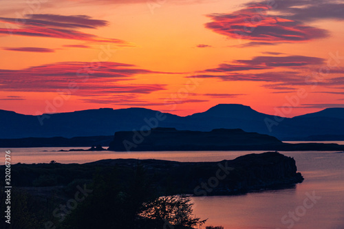 Silhouette of a man sitting on a bench at beautiful sunset. View of the Isle of Skye. Scotland landscape.