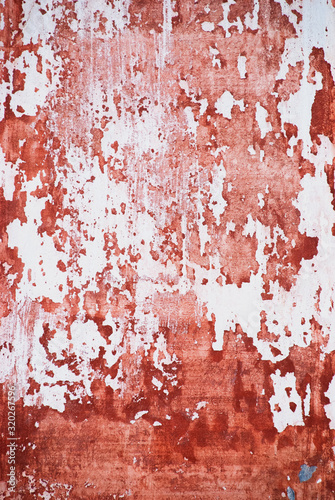 Old heavily worn wall with peeling white and red paint. Wallpaper of the old wall.