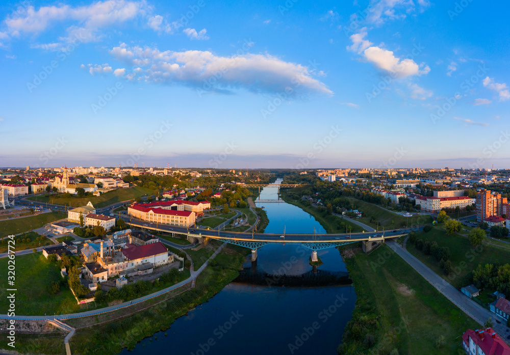 Obraz premium Panoramic view of the city of Grodno, the embankment, the Neman river and the old city. Autumn evening, the city in the sunshine against a background the blue sky.