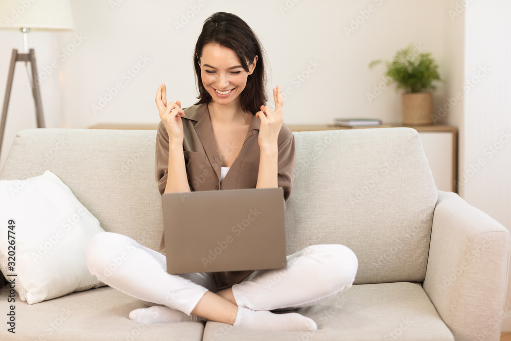 Cheerful young girl crossing fingers using laptop Cheerful young girl crossing fingers using laptop