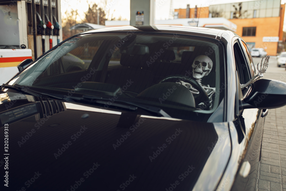 Skeleton in car, fueling on gas station