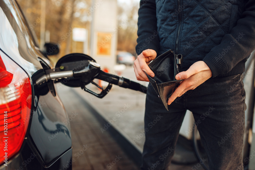 Obraz premium Man with empty purse on gas station, fuel filling