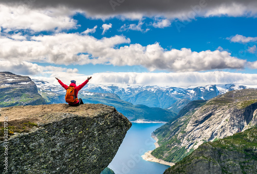 Travel concept. Hiker woman sitting on a cliff over a lake, Trolltunga, Norway. Artistic picture. Beauty world. The feeling of complete freedom © olenatur