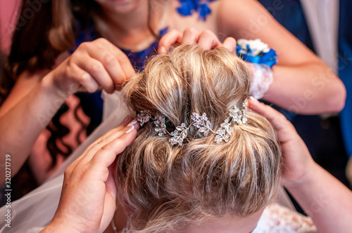 Bridesmaid helps the bride with her hairstyle