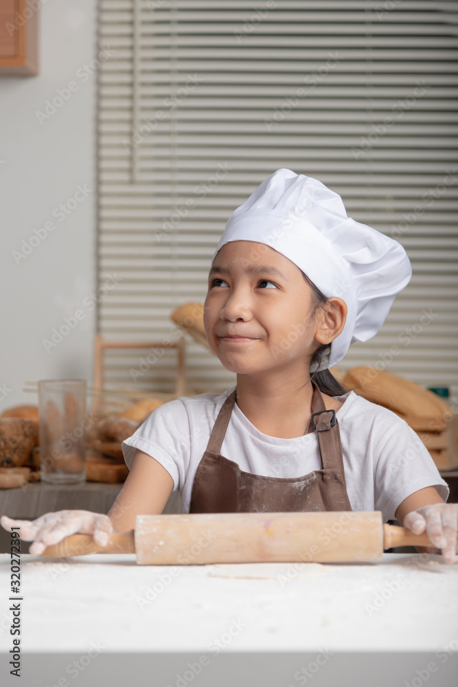 A child wearing a white chef hat and smiling with happiness. A child wearing a white chef hat and smiling with happiness.