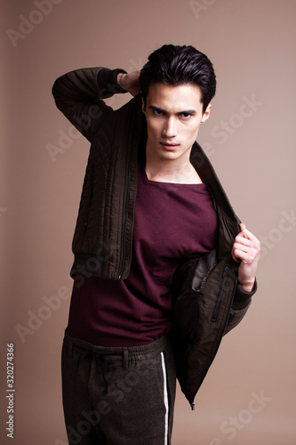 young pretty asian man posing in fashion style on light brown background, lifestyle people concept