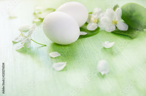 Apple trees flowers and green leaves. Chicken white eggs on wooden table background. Easter and spring.