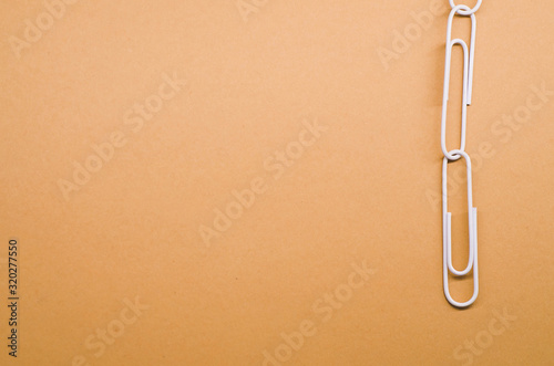 white paper clips connected with each other on a brown background