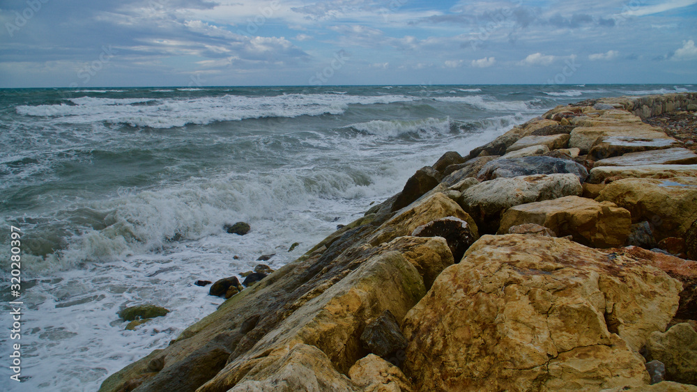 Breakwater and sunset views in the Mediterranean. Wavy sea and people.