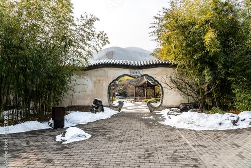 Beijing Botanical Garden Jixiu Garden after clear winter snow. Chinese translation on the Moon Gate: a garden of many green beautiful plants photo