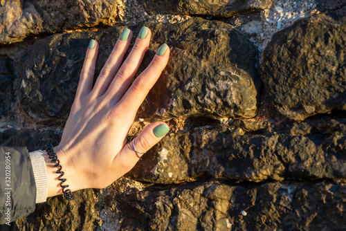 Quadro em tela Female hand with manicure on a background of stones