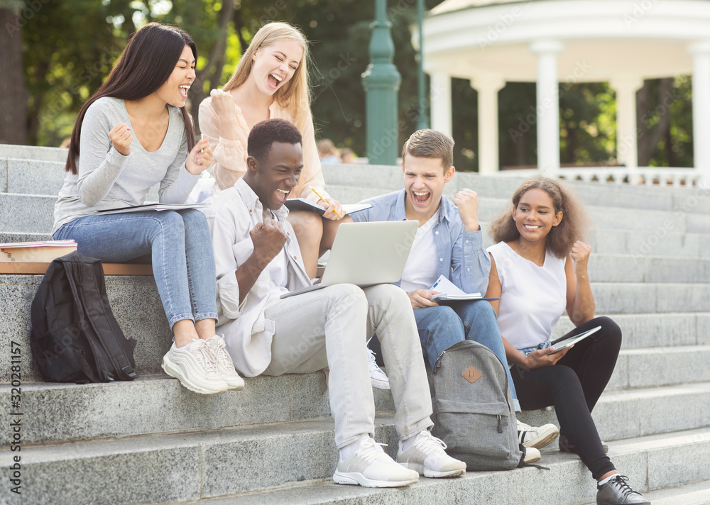 Group of students celebrating success, checking exam results online