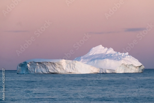 Goergeous sunset over giant icebergs and stunning polar landscapes along the coast of the Antarctic Peninsula