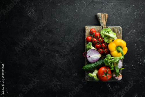 Ripe vegetables. Fresh vegetables on black stone background. Tropical fruits. Top view. Free space for your text.