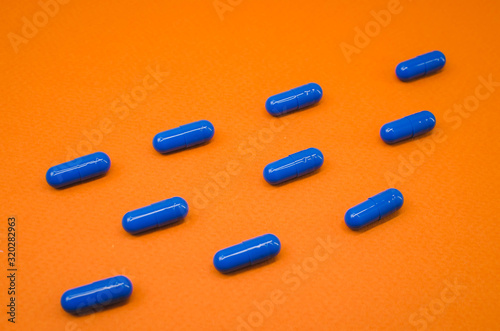 blue capsule tablets on an orange background