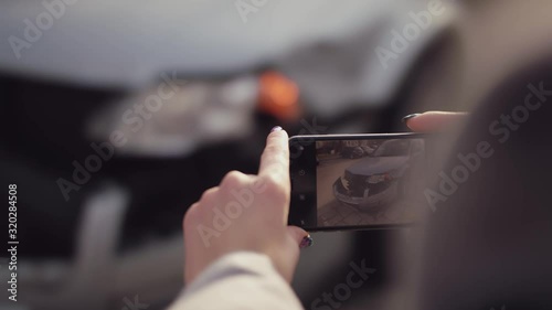 Woman takes a photo on her smartphone after crash of a broken car. Tracking shot, panning right.