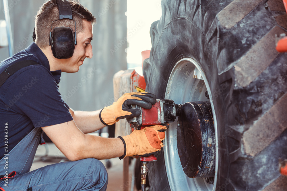 Farm machine mechanic working on wheel StockFoto Adobe Stock