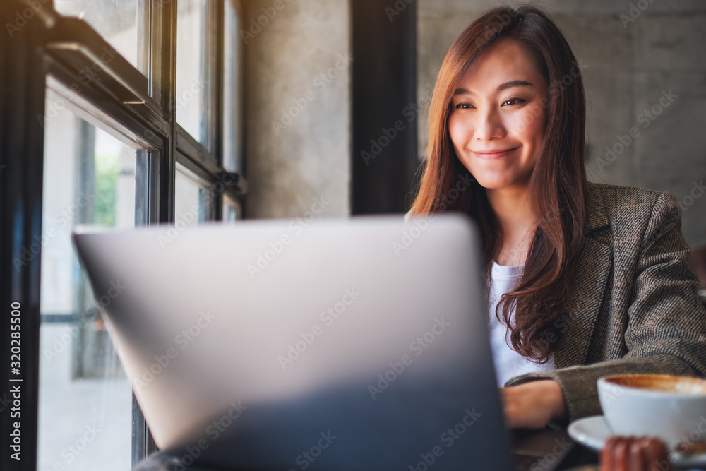 Fototapeta premium Closeup image of a woman working and typing on laptop computer in cafe