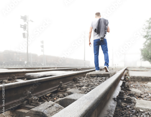 Young man going along railway track. Concept of choice