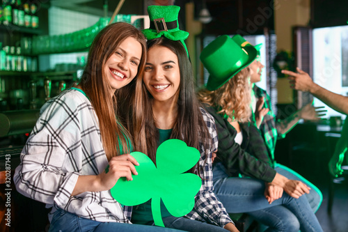 Obraz na płótnie Young women celebrating St. Patrick's Day in pub