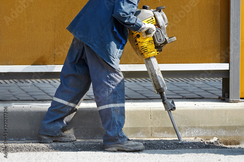 Принти на полотні Worker with pneumatic demolition hammer breaking asphalt at road construction site
