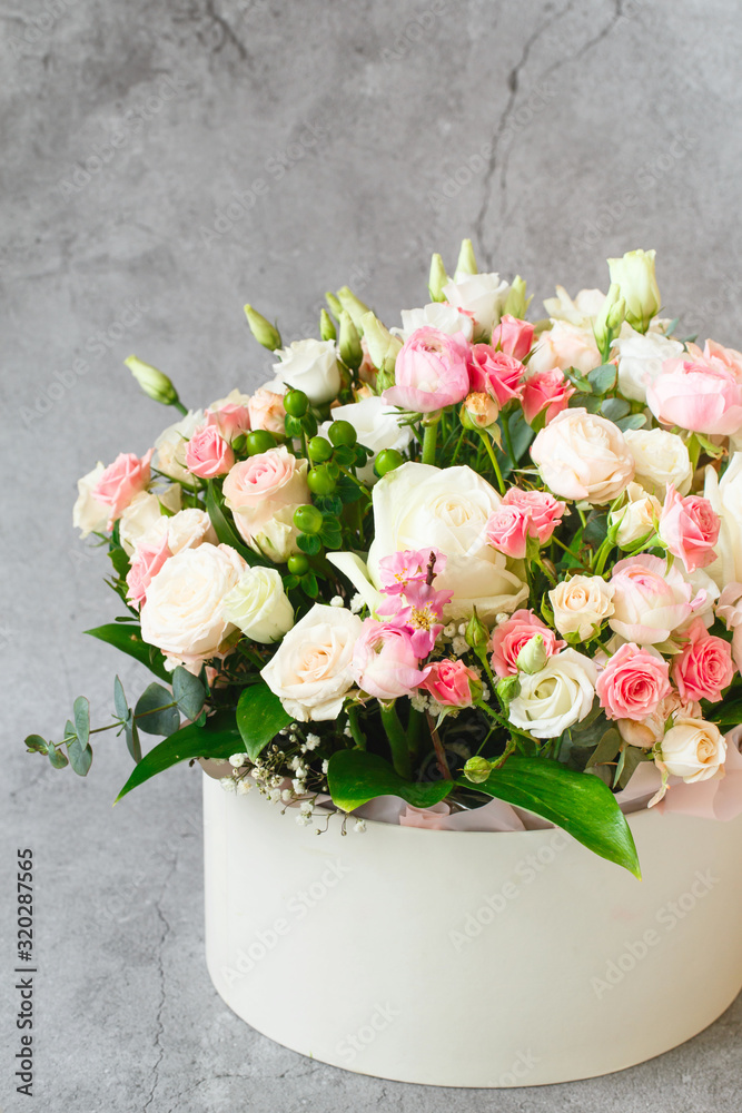 Bouquet of beautiful flowers with peonies, roses and eustomas in the papper gift box in front of grey grunge background. Closeup picture. Valentine's Day. Mothers Day Bouquet of beautiful flowers with peonies, roses and eustomas in the papper gift box in front of grey grunge background. Closeup picture. Valentine's Day. Mothers Day