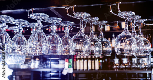 Wine and martini glasses in shelf above a bar rack in restaurant. 