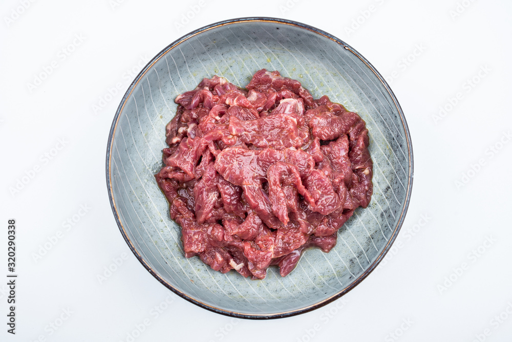 Fresh marinated beef slices on a plate on white background Fresh marinated beef slices on a plate on white background