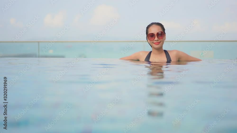 An attractive woman chest deep in a swimming pool relaxes t in its water,