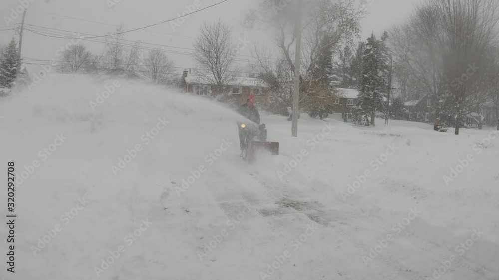 Man uses snow blower to clear driveway after heavy snowfall Man uses snow blower to clear driveway after heavy snowfall