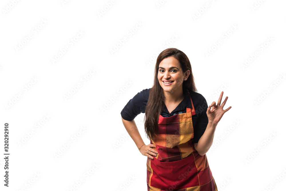 Portrait of Indian woman chef or cook in apron, presenting, pointing, with ok sign, thumbs up or