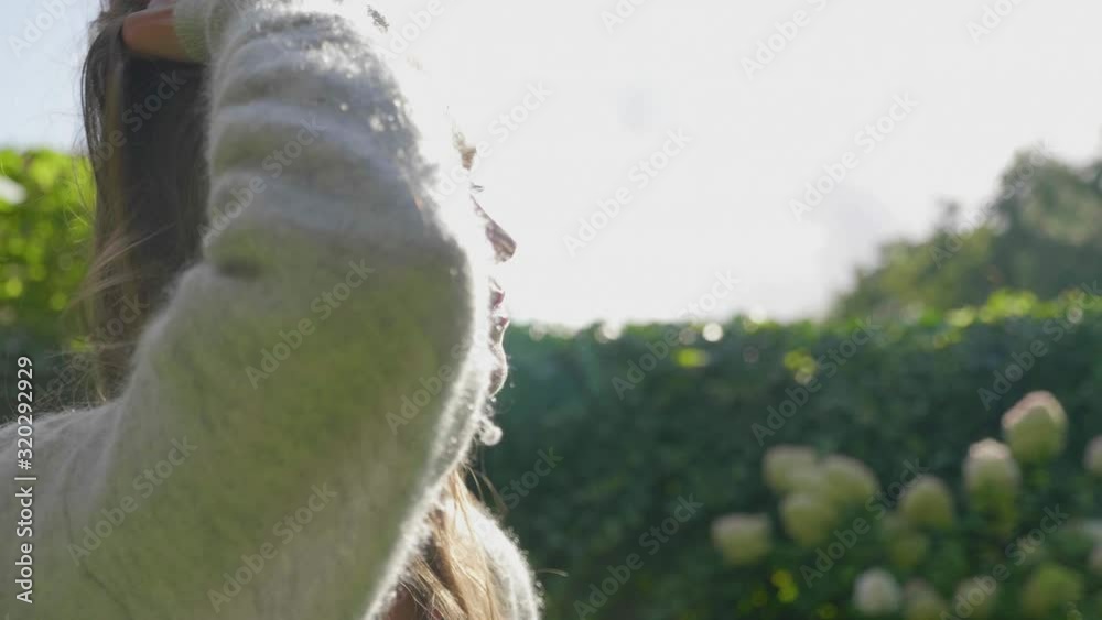 Attractive woman in a beautiful sunny garden fondling her hair looking in the distance, slow motion close up Attractive woman in a beautiful sunny garden fondling her hair looking in the distance, slow motion close up